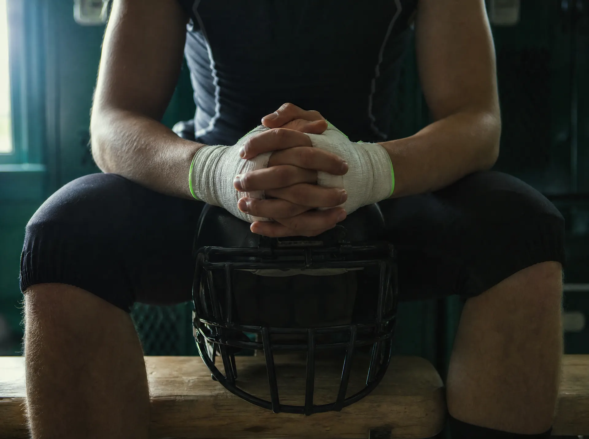 An athlete's taped hands clasped in prayer on a helmet
